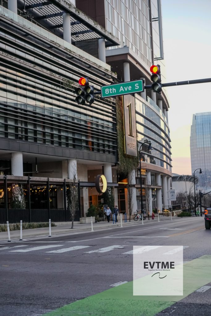 Intersection at 8th Ave S with red traffic lights, a modern glass building, and a hotel sign along the street
